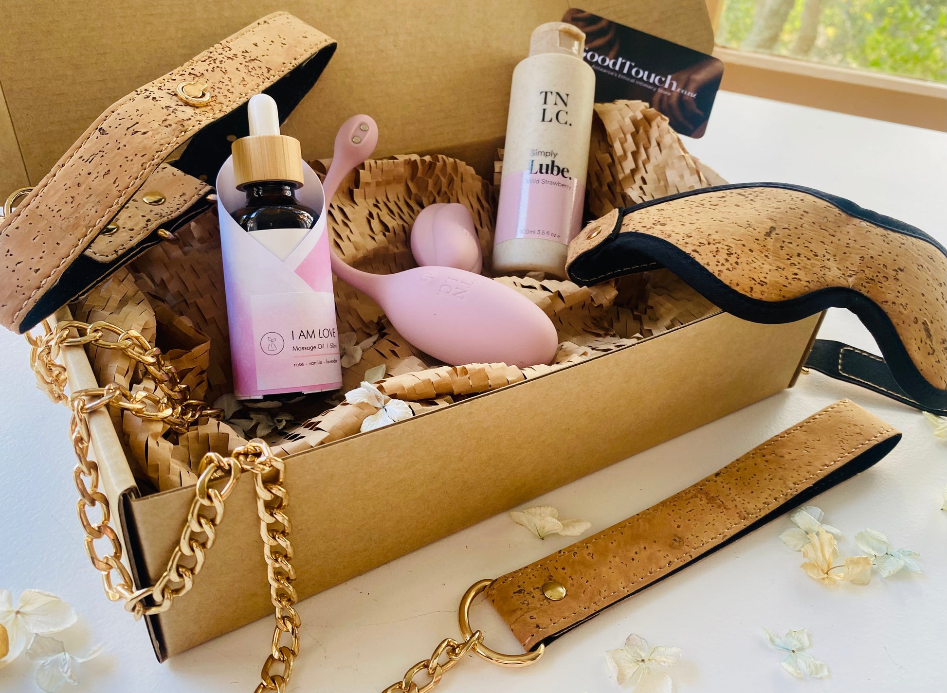 Bondage & Toy Bundle presented in a gift box, including a bottle of massage oil, a pink remote-controlled love egg, a cork leather blindfold, and a chocker & leash.